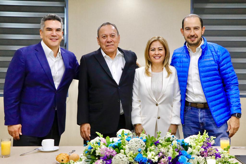 Un grupo de personas posando junto a un pastel Descripción generada automáticamente