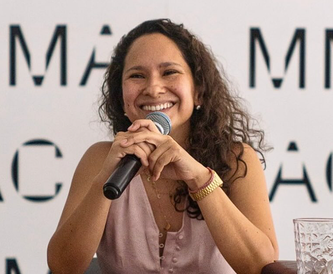 Una mujer con un micrófono en la mano Descripción generada automáticamente con confianza baja