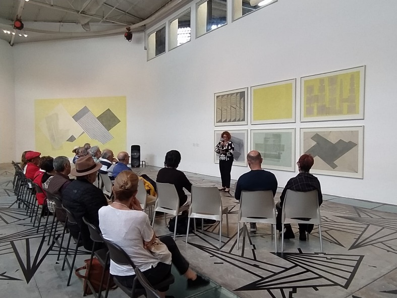 Un grupo de personas sentadas en una sala Descripción generada automáticamente con confianza media