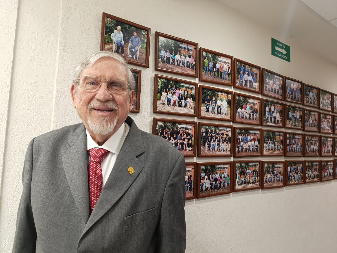 Un hombre con traje y corbata posando para una foto Descripción generada automáticamente