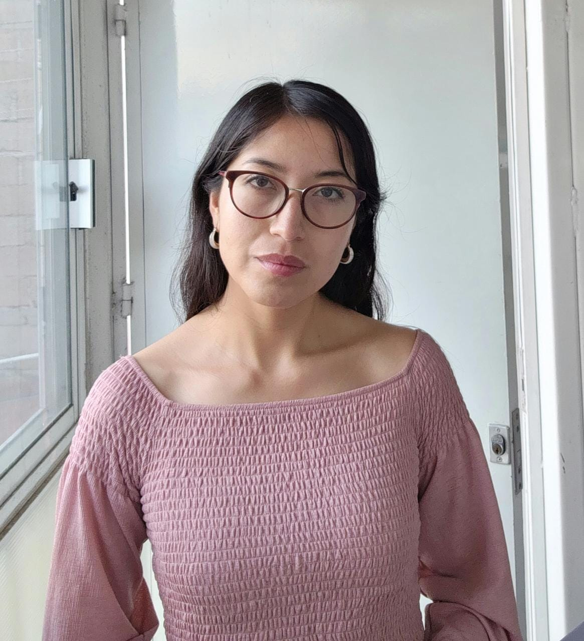 Mujer con suéter gris posando para la cámara delante de una ventana El contenido generado por IA puede ser incorrecto.